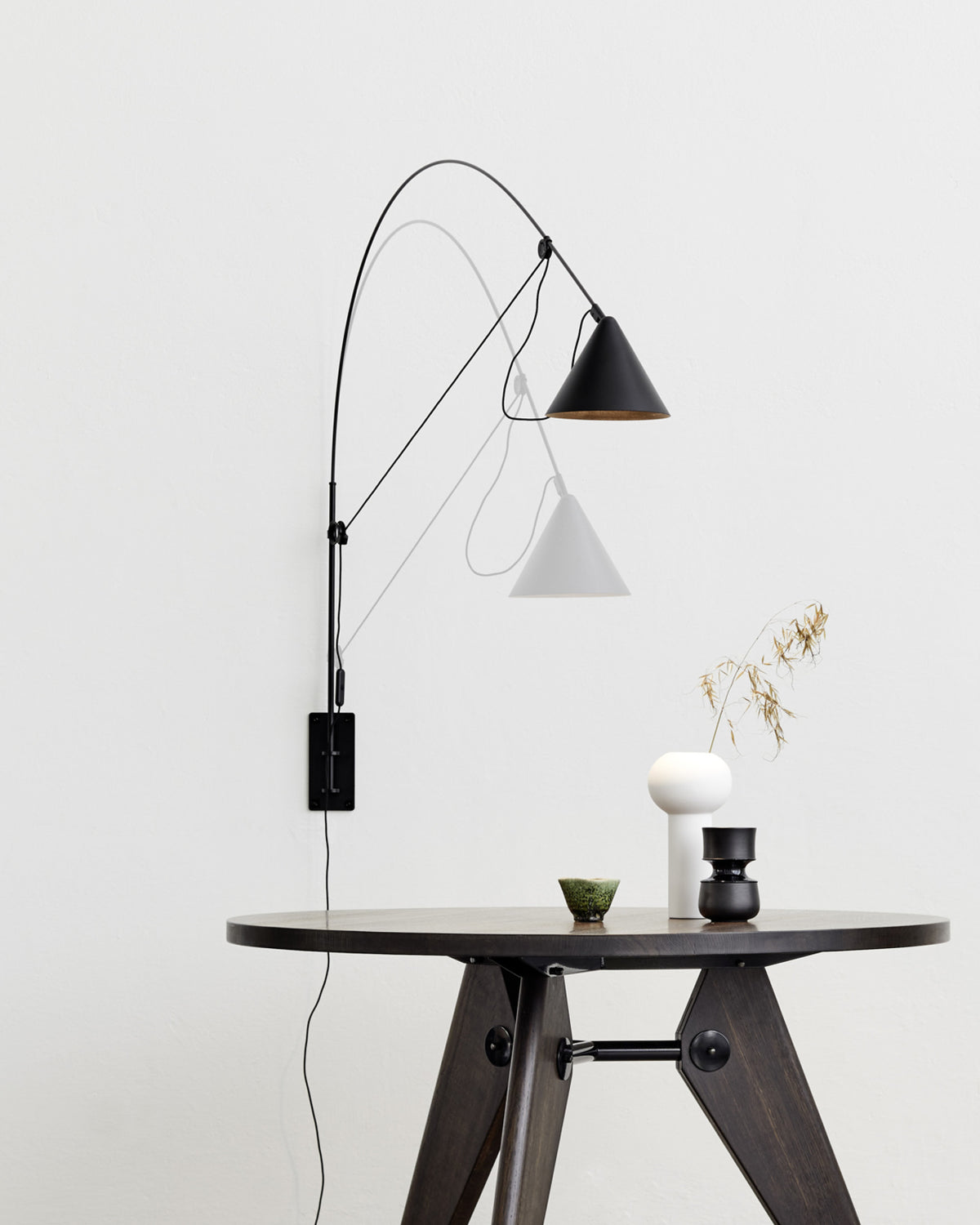 Midgard AYNO L adjustable wall lamp in black illuminating a dining table in a modern interior