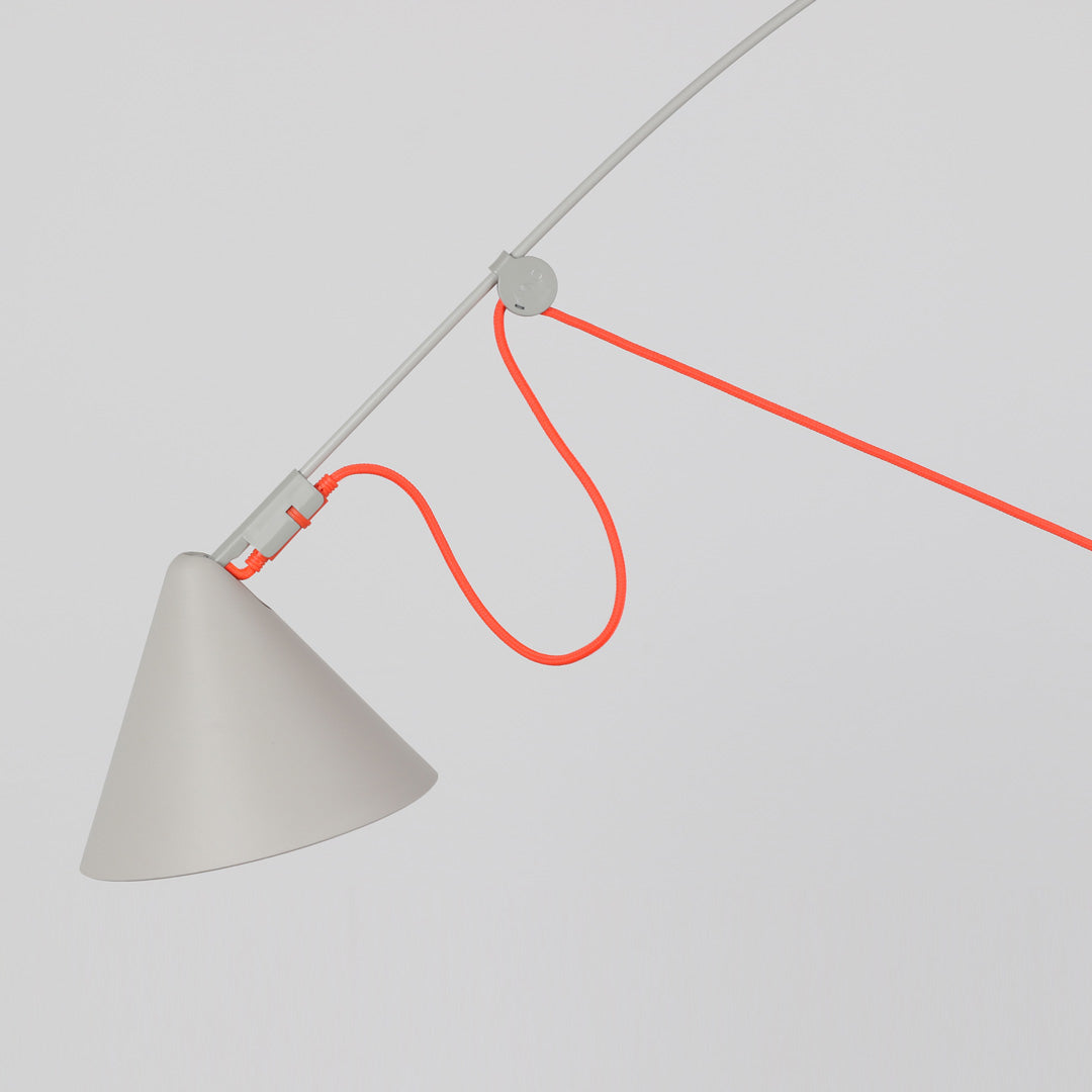 Close up detail of a contemporary arc-style floor lamp in matte silk grey with neon orange textile cable