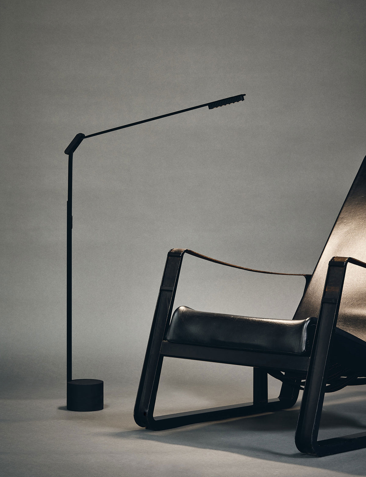 RAY by Midgard adjustable floor lamp beside a black lounge chair