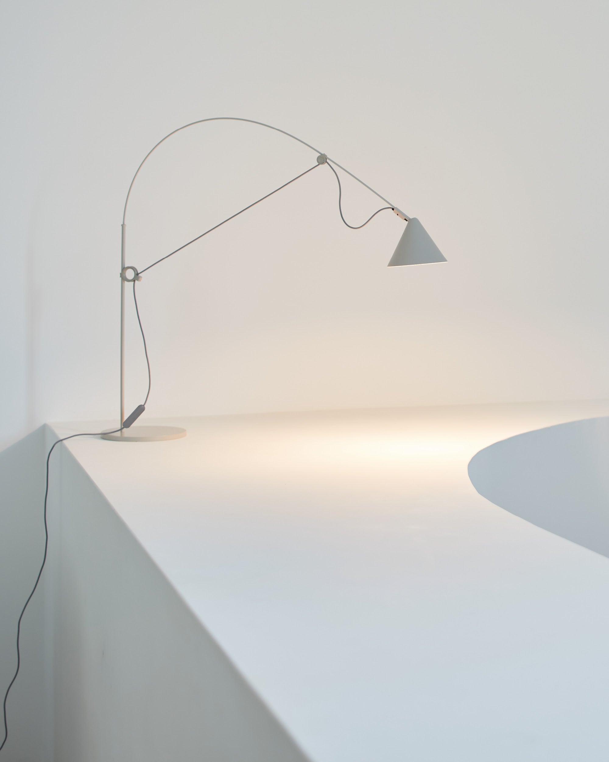 Midgard AYNO S adjustable table lamp in silk grey illuminating a table in a modern interior