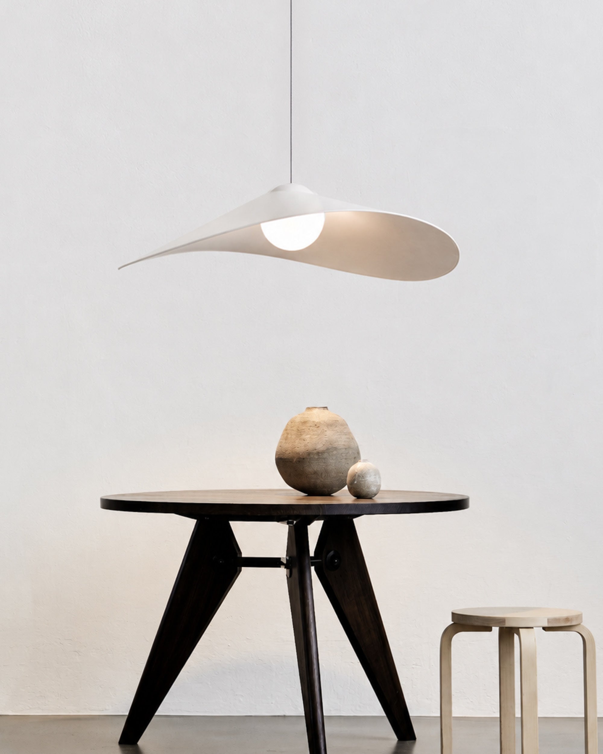 LOJA pendant lamp by Sebastian Herkner for Midgard, with a curved paper shade creating an interplay of direct and indirect light.