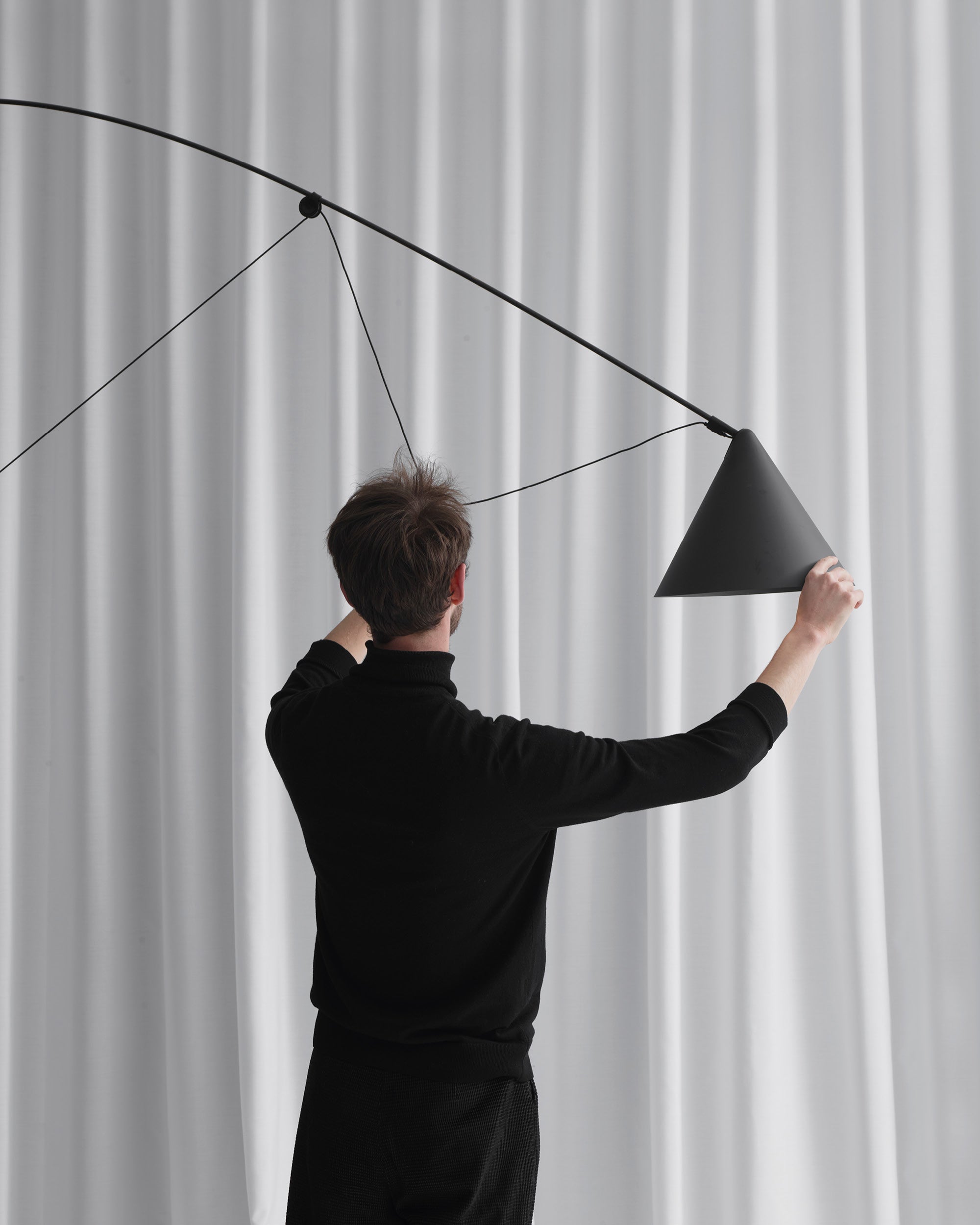Midgard AYNO XL adjustable floor lamp in black demonstrating its patented adjustment principle and exceptional reach