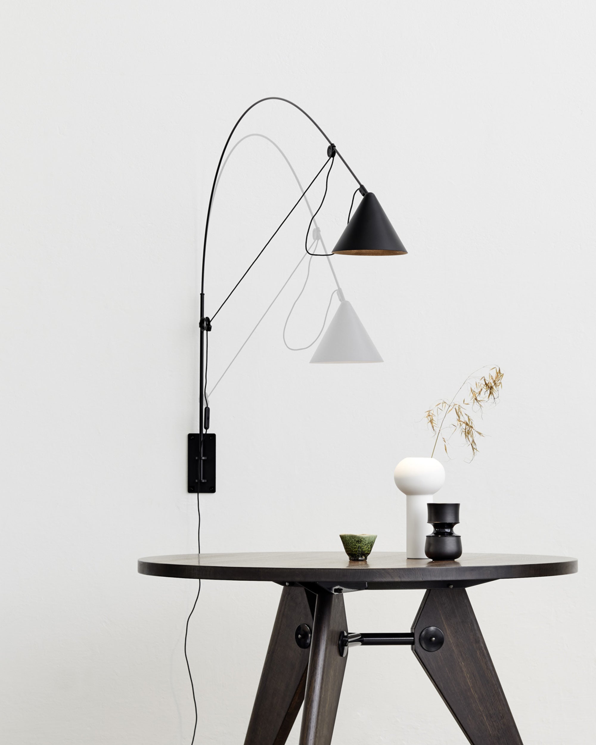 Midgard AYNO L adjustable wall lamp in black illuminating a dining table in a modern interior