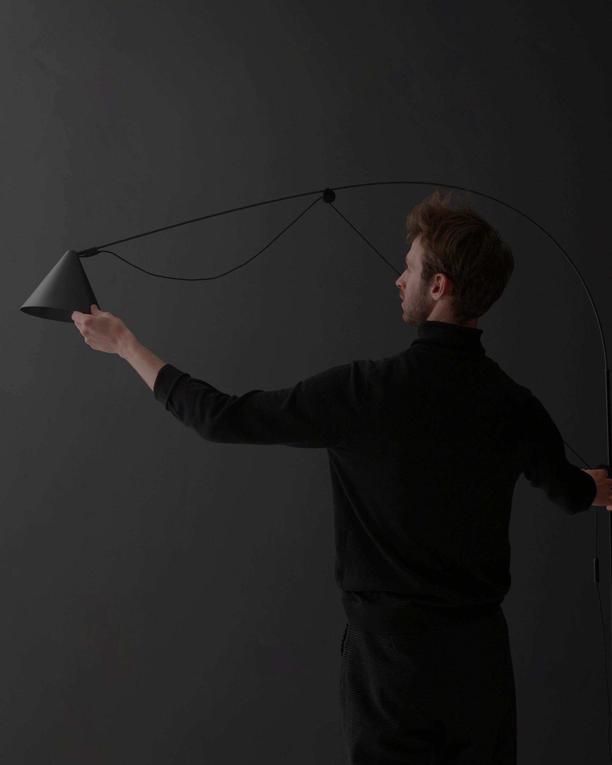 Midgard AYNO L adjustable wall lamp in black demonstrating its patented adjustment principle and flexible reach