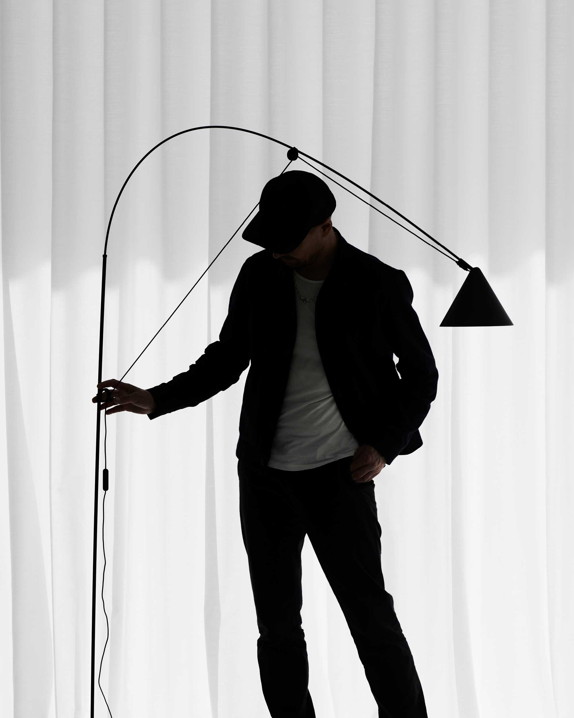 Midgard AYNO L adjustable floor lamp in black designed by Stefan Diez, demonstrating its flexible reach