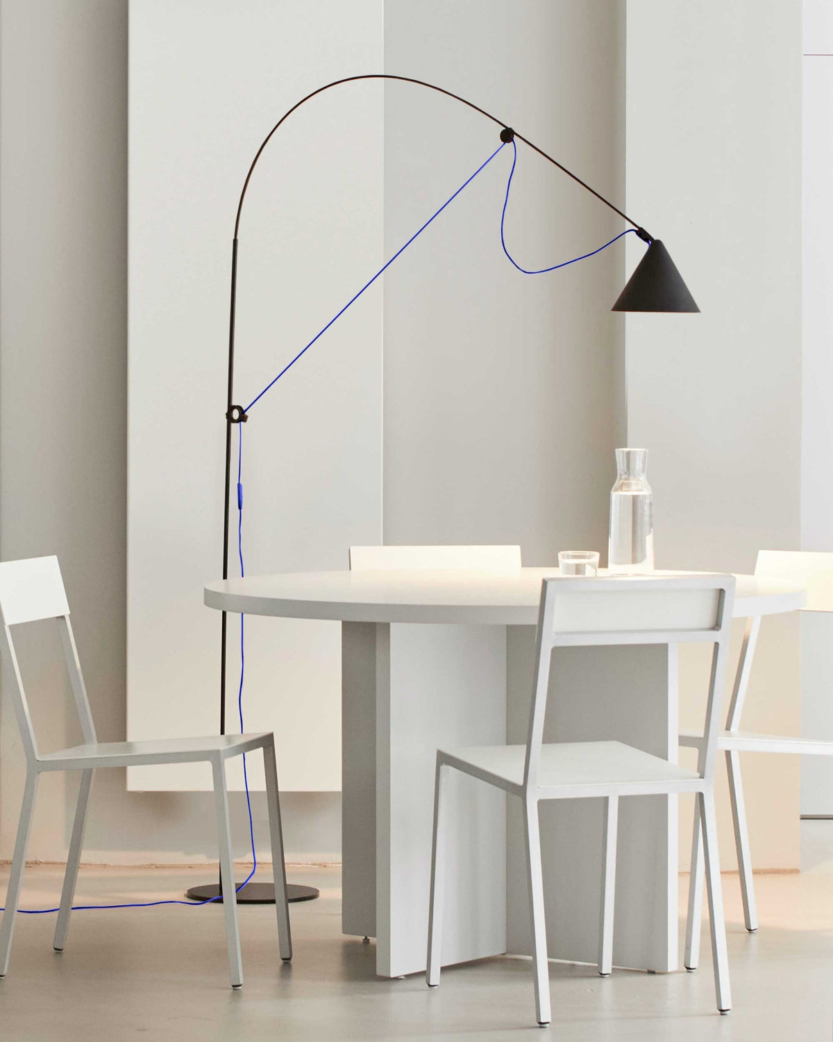 Midgard AYNO L adjustable floor lamp in black with ultramarine blue cable beside a dining table