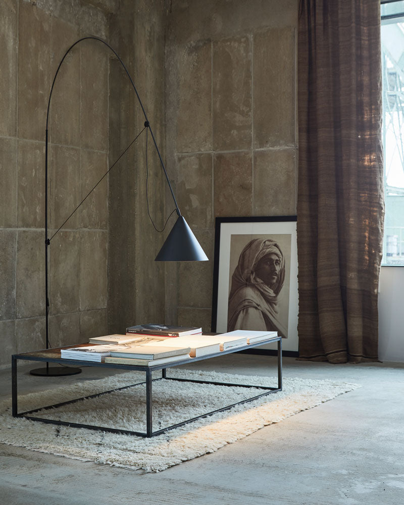 AYNO XL floor lamp designed by Stefan Diez for Midgard in an interior setting, providing adjustable light over a low table.