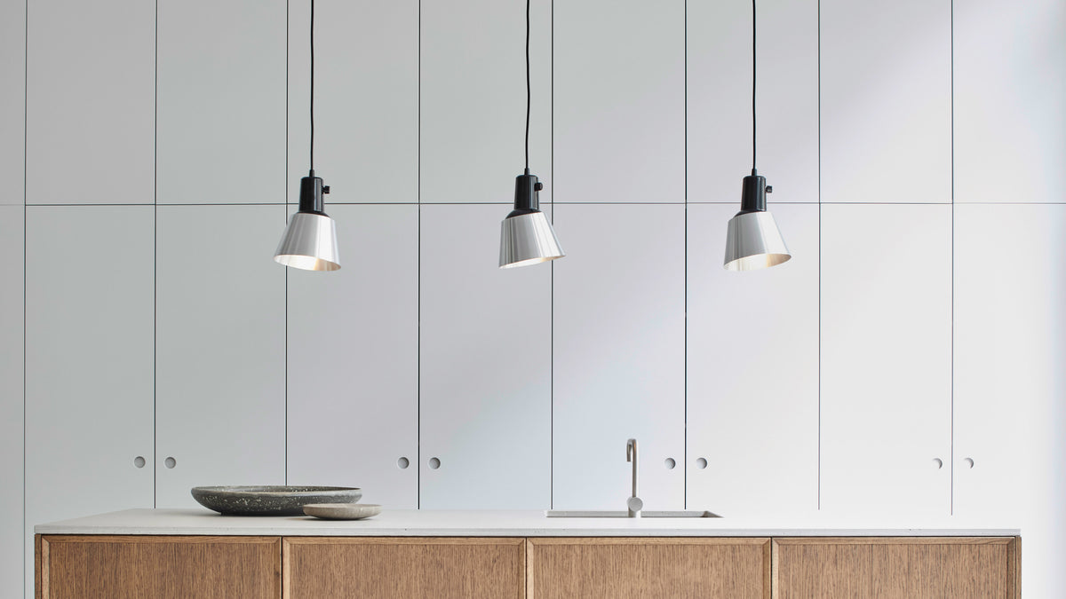 Three Midgard K831 pendant lamps above a modern kitchen island with adjustable lampshades providing directional light.