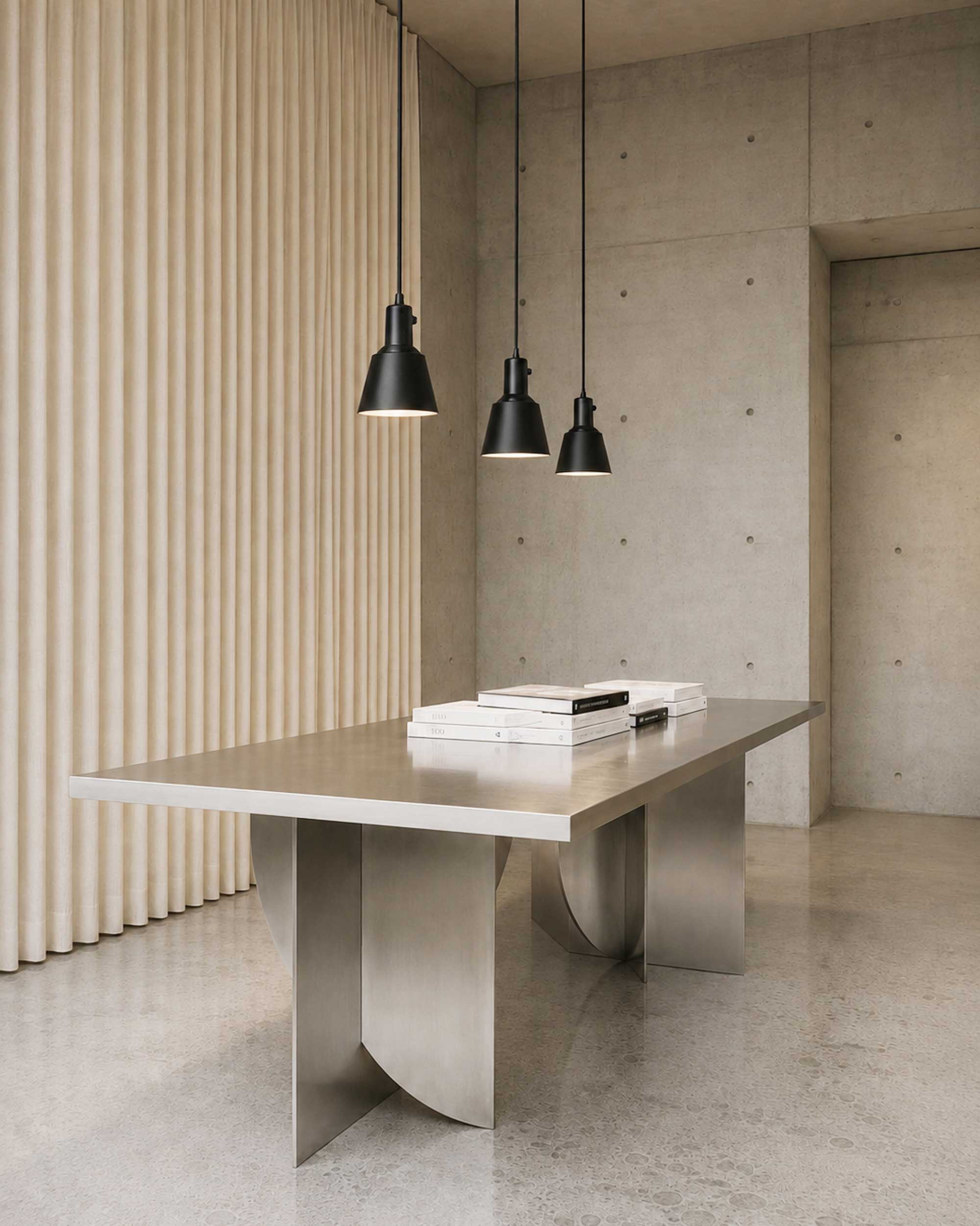 Three Midgard K831 pendant lamps in powder-coated black above a dining table providing directional light.